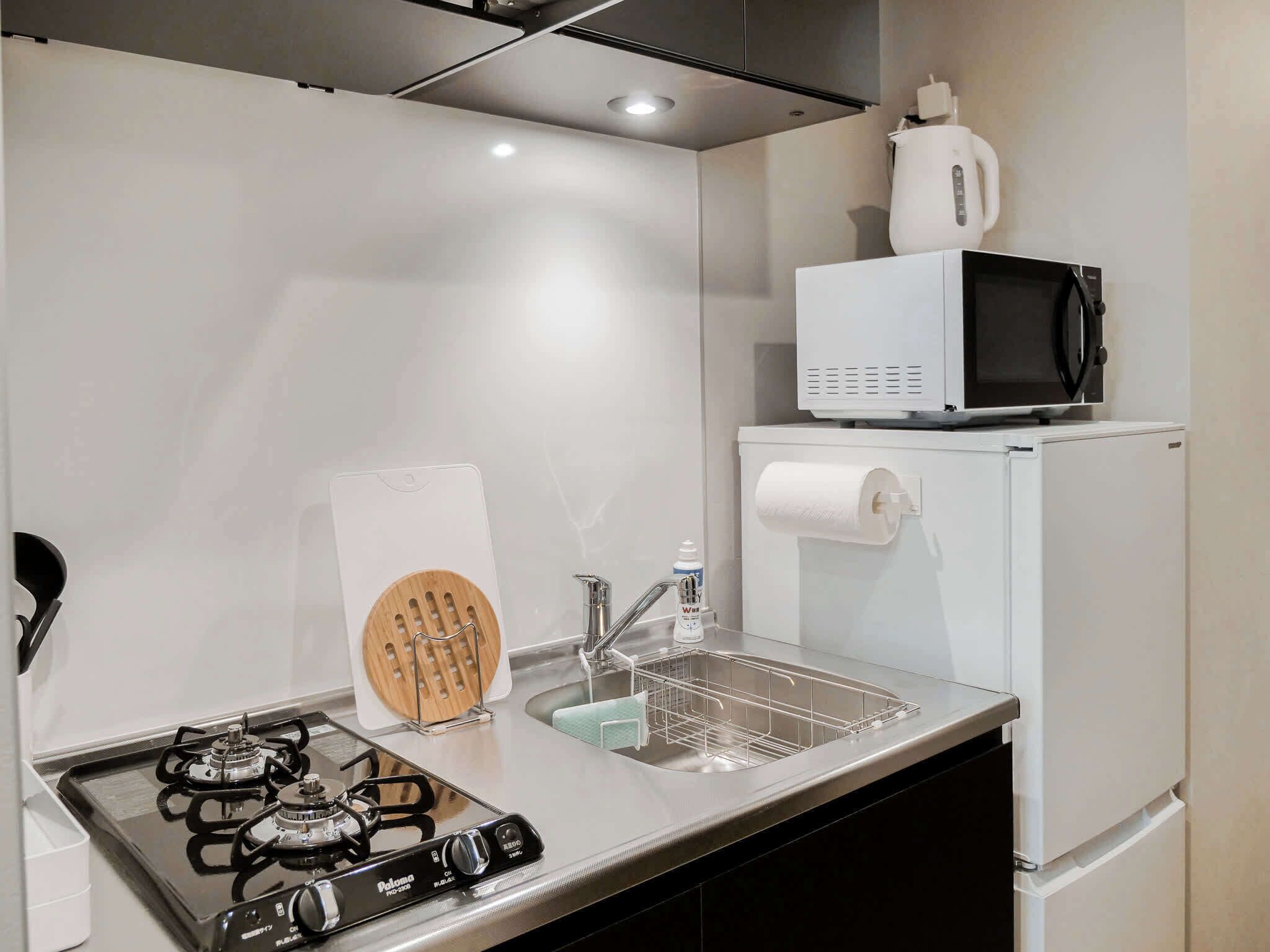 Een moderne keuken met een gasfornuis, een roestvrijstalen spoelbak en een magnetron.