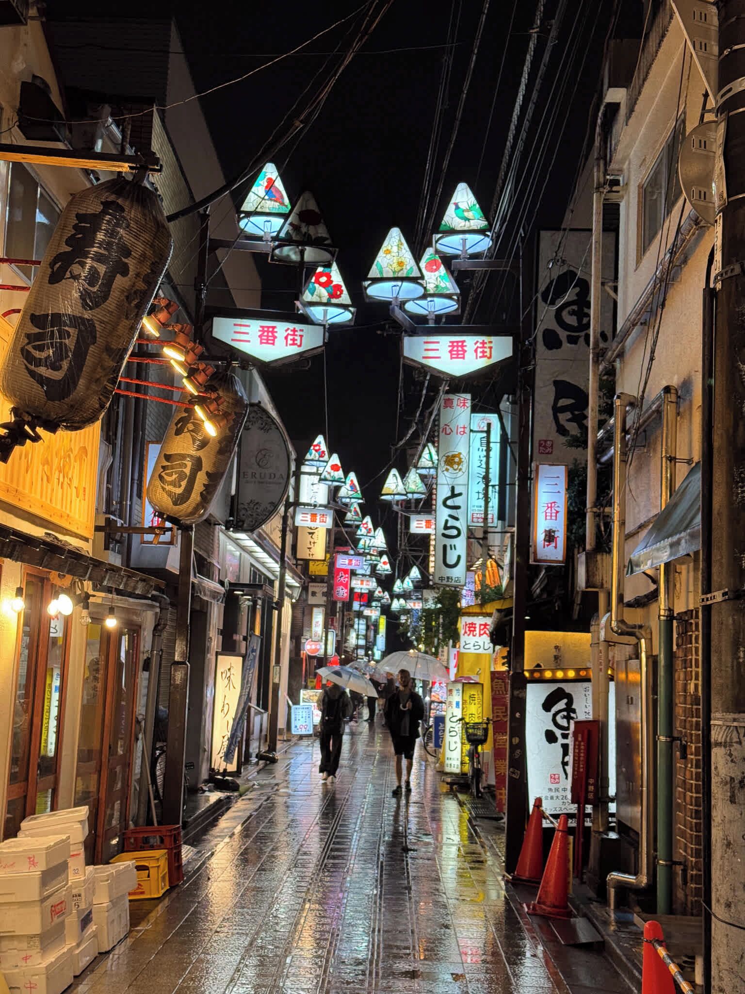 Una calle estrecha con señalización tradicional y faroles, que indica una zona histórica o cultural.