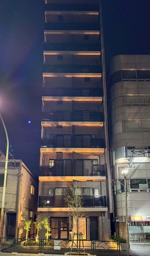 A multi-story building with a modern architectural design, featuring a series of balconies and a central entrance.