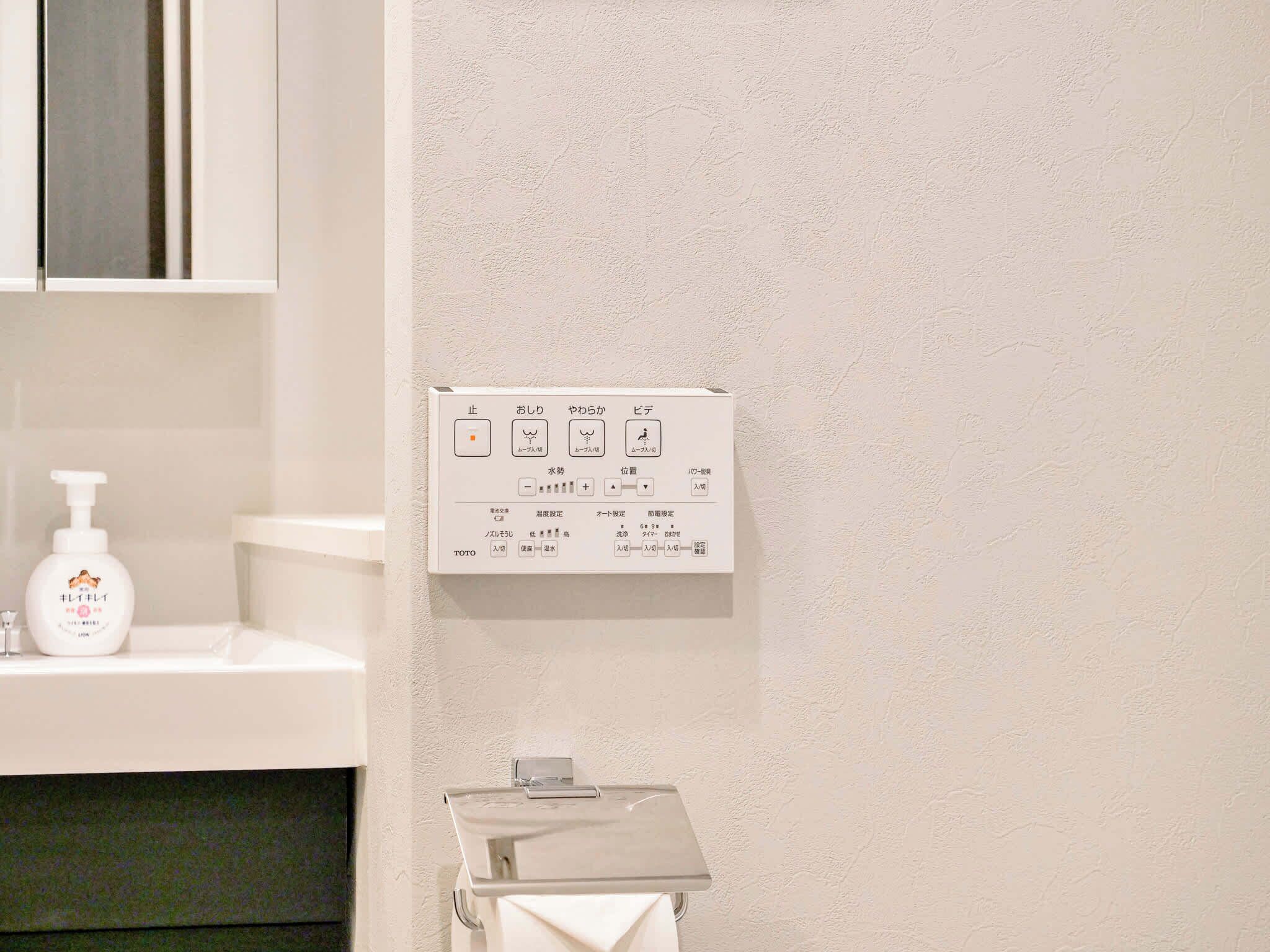Une salle de bain avec un mur blanc, un lavabo blanc, un flacon de lotion blanc et un distributeur de serviettes blanc.