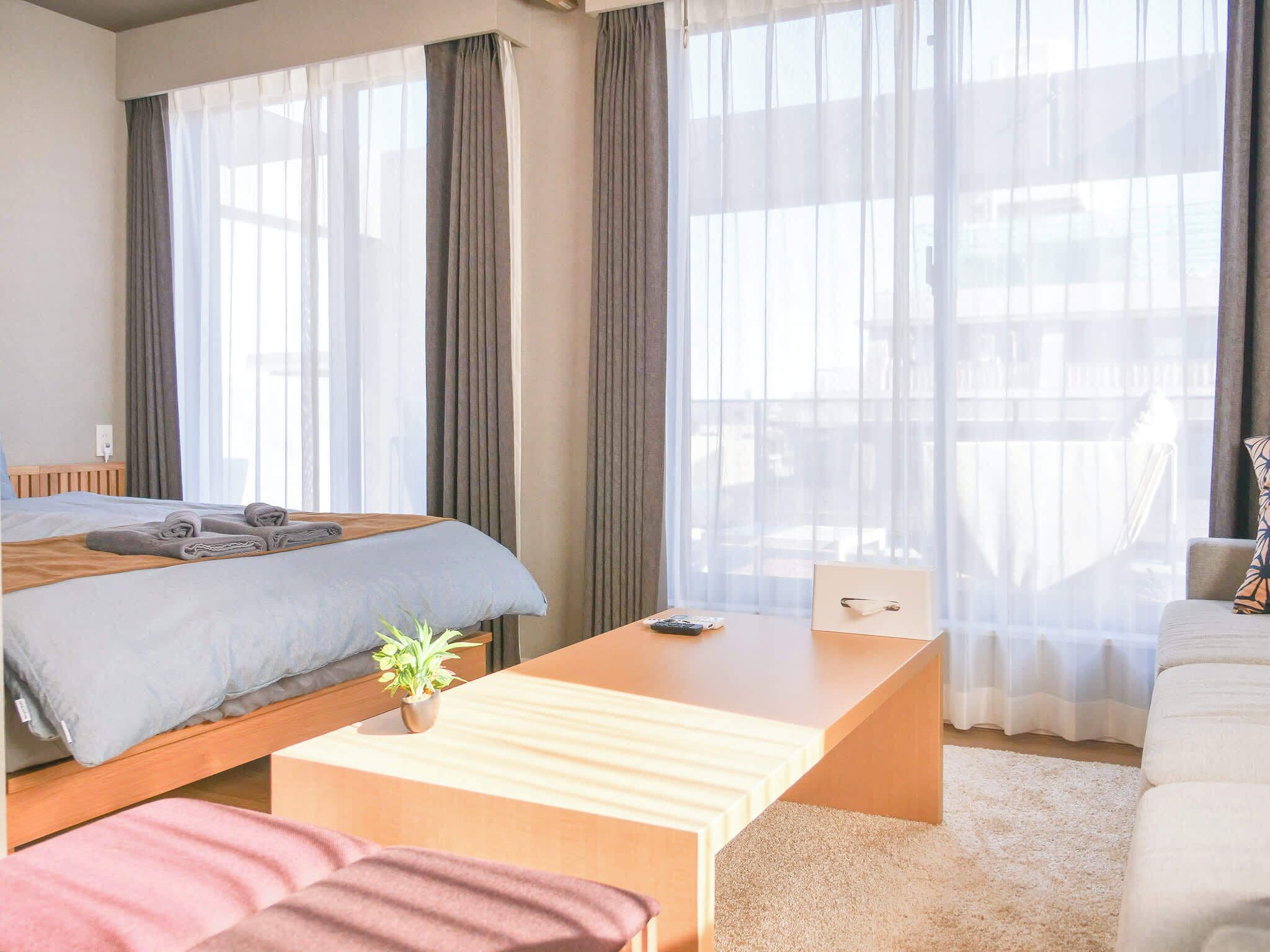 A hotel room with a bed, a desk, a chair, and a sofa.