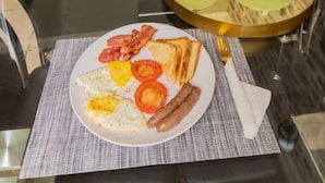 A dining area with a glass table, black chairs, and a variety of breakfast items including eggs, bacon, and toast.