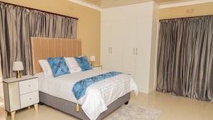 A bedroom with a bed, nightstands, a wardrobe, and curtains.
