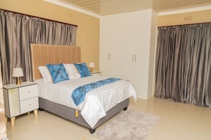 Un dormitorio con cama, mesitas de noche, armario y cortinas.