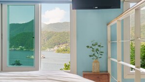 A bedroom with a large window offering a view of a lake and mountains. - Gapyeong Nami Island Pool & Spa Pension (Gapyeong)
