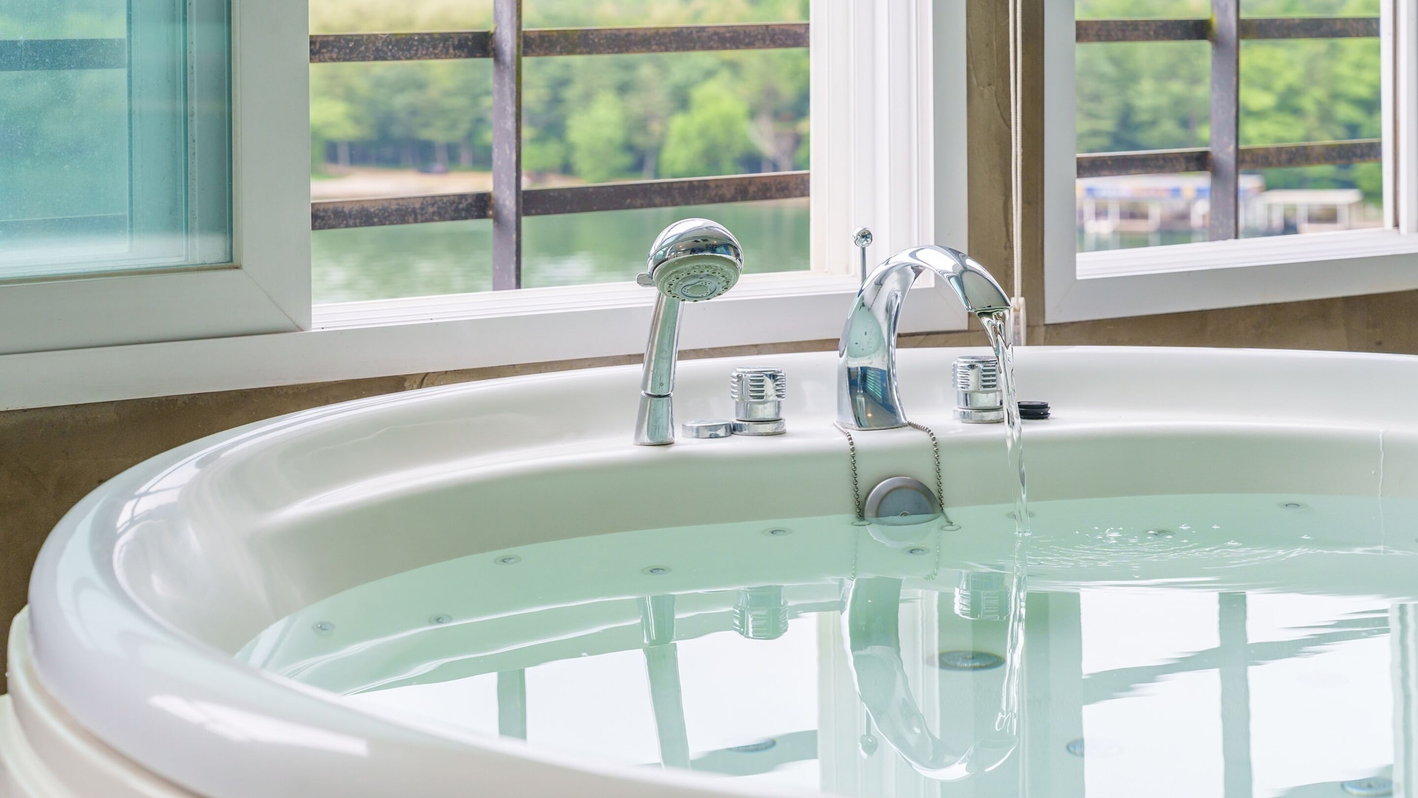 A large, oval-shaped bathtub with two faucets, a showerhead, and a drain.