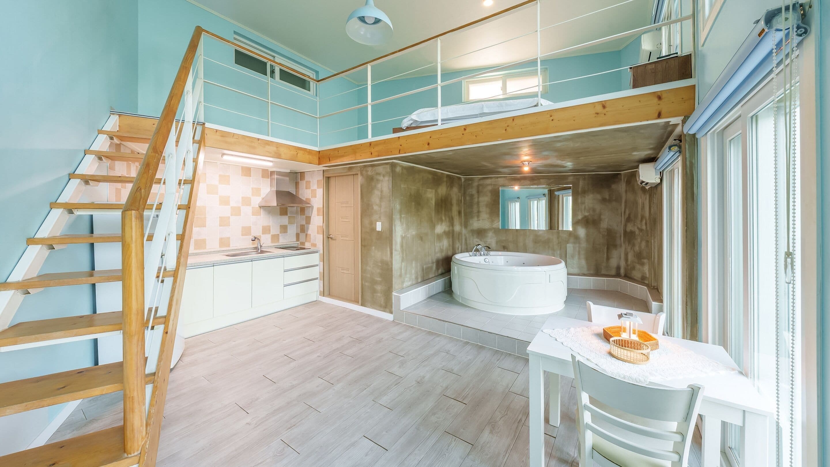 Ein geräumiges Zimmer mit einer Holztreppe, einer großen Badewanne und einem kleinen Tischchen mit einem Korb.