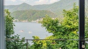 A lake with boats, surrounded by lush green hills and buildings in the distance. - Gapyeong Nami Island Pool & Spa Pension (Gapyeong)