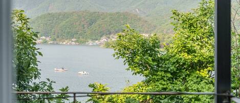 A lake with boats, surrounded by lush green hills and buildings in the distance.