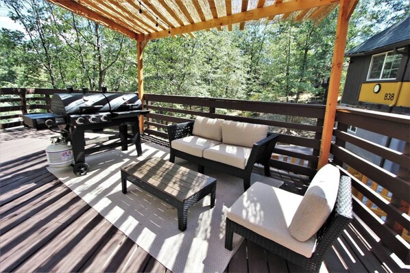 A wooden deck with outdoor furniture, including a sofa and chairs, and a barbecue grill. - The Train Getaway (Big Bear Lake)