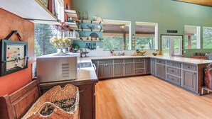 A kitchen with wooden cabinets, a large island, and a view of the outdoors. - Rustic & Modern Home w/ Forest Views in Newport! (Newport)
