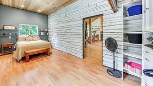 A bedroom with a wooden ceiling, a bed with a bench, a fan, and a wardrobe with shelves. - Rustic & Modern Home w/ Forest Views in Newport! (Newport)