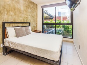 A neatly made bed in a hotel room with a large window offering a view of the outdoors.