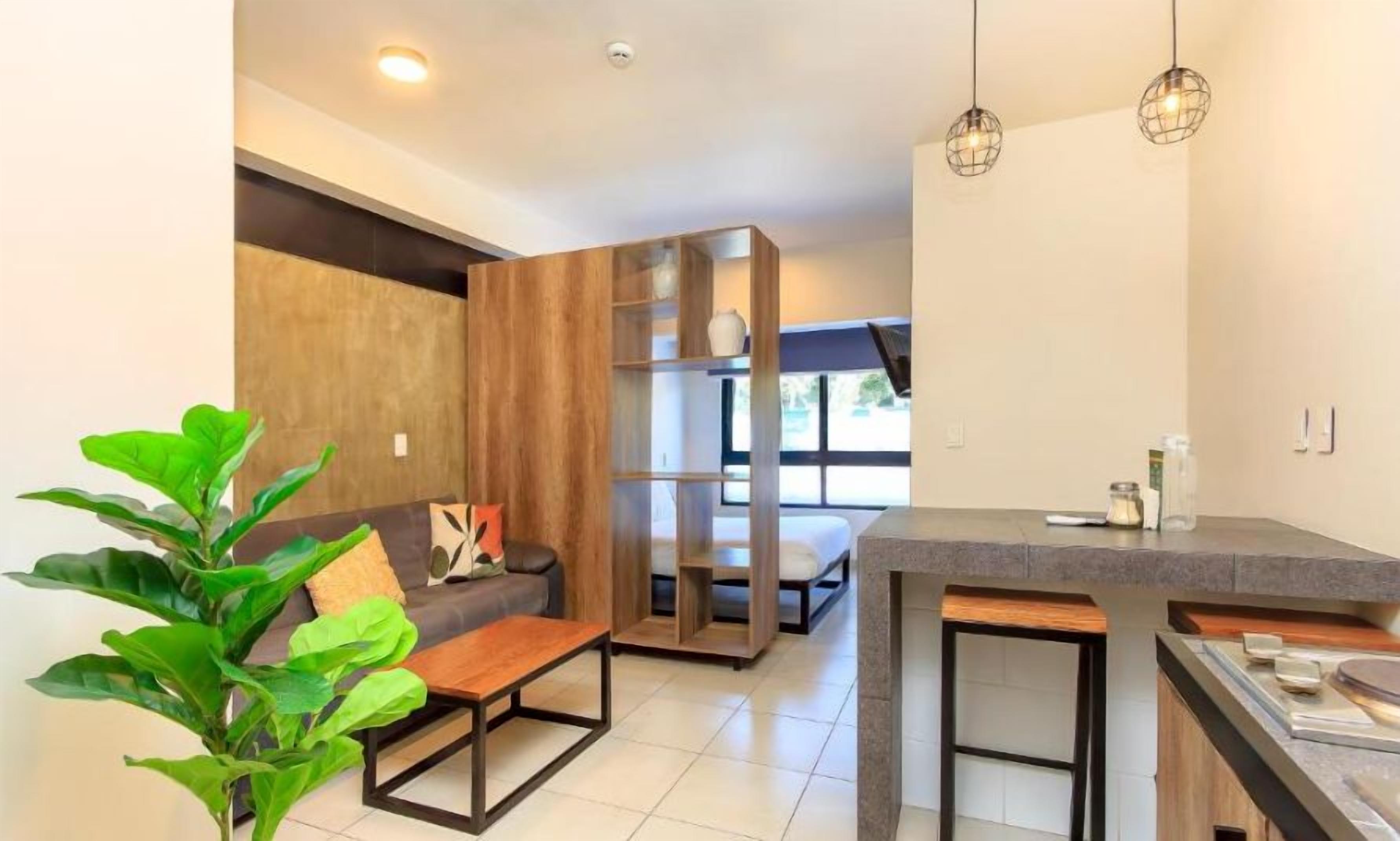Un espacio habitable moderno con sofá, mesa de centro y comedor con mostrador.