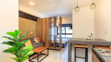 Un espacio habitable moderno con sofá, mesa de centro y comedor con mostrador.