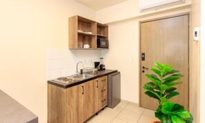 A compact kitchen with wooden cabinets, a microwave, and a sink. - Rau Departamentos (Guadalajara)