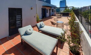 A rooftop terrace with two lounge chairs, a small table, and a seating area. - Rau Departamentos (Guadalajara)
