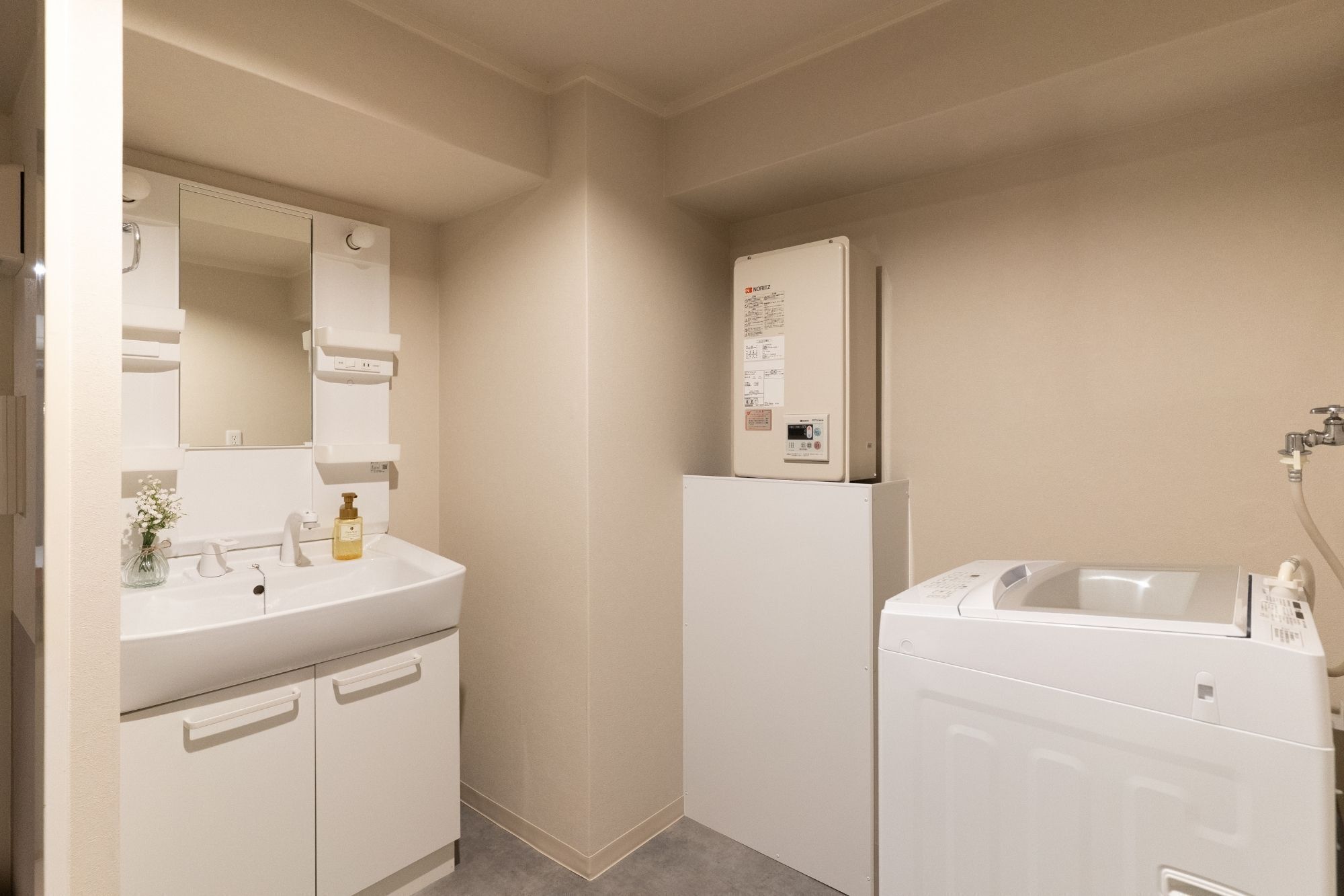 Une salle de bain avec un lavabo blanc, un miroir et un lave-linge blanc.