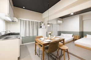 Une chambre d’hôtel compacte comprenant un coin cuisine, un espace repas, un lit et une table de chevet.