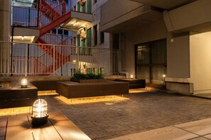 An outdoor seating area with a fire pit, benches, and a red staircase. - Hotel LEGALIE Osaka Shinsaibashi East (Osaka)