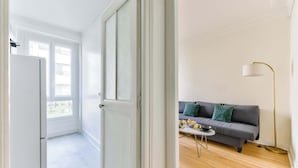 Ein modernes Wohnzimmer mit grauem Sofa, einem kleinen Tisch und einer Stehlampe.