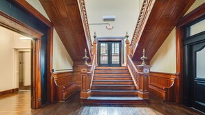 A grand staircase with wooden railings and a black door at the top. - Historic Downtown Marshall: Efficient Studio Space (Marshall)