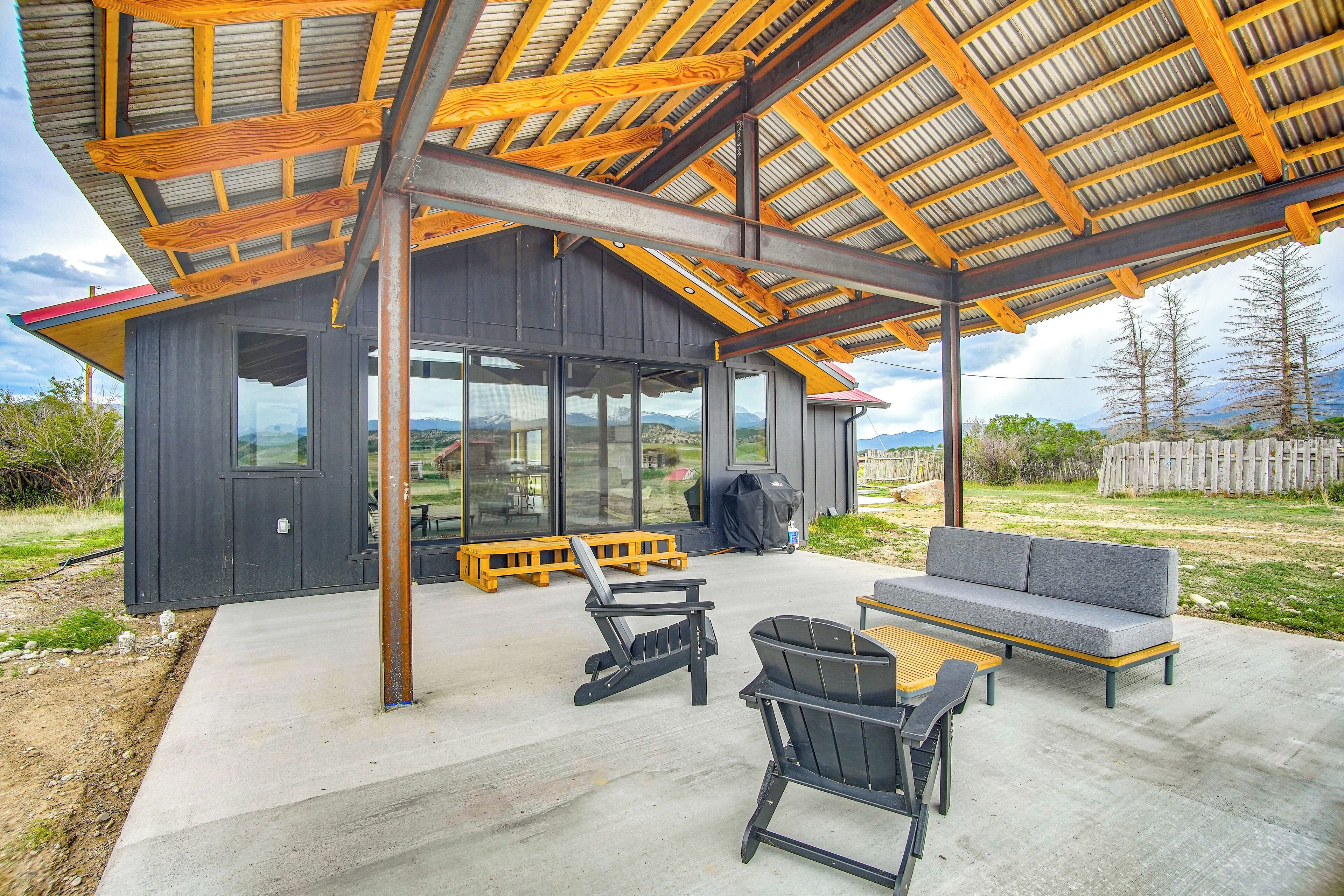 Uma casa moderna com varanda coberta, área de estar externa e vista para as montanhas.