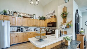 Una cocina con armarios de madera, un refrigerador de acero inoxidable, una encimera de granito y diversos electrodomésticos.
