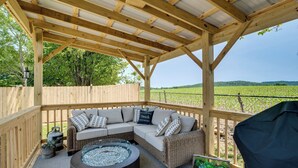 Un espacio al aire libre cubierto con un sofá modular acolchado, una mesa de centro redonda y una estructura de pérgola.