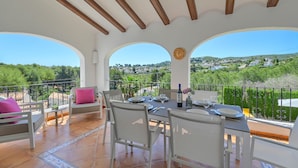 A terrace with a table set for dining, white chairs, and a sofa with pink cushions. - Ines Isabel - Javea, Costa Blanca (Javea)