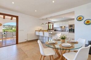 A modern kitchen with white cabinets, stainless steel appliances, and a dining area with a glass table and white chairs.