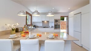 A modern kitchen with a central island, white cabinetry, and pendant lighting. - Ines Isabel - Javea, Costa Blanca (Javea)