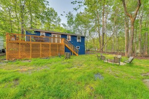 A blue cabin with a wooden deck and a fire pit area. - Game Room & Deck: Family Home in Tobyhanna! (Tobyhanna)