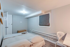 A bedroom with a bed, a chair, a window, a heater, and a door. - Game Room & Deck: Family Home in Tobyhanna! (Tobyhanna)