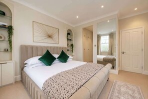 A bedroom with a bed, a bedside table, a mirror, and a wardrobe. - Chelsea 4‑BR, 4 Ensuites | Roof Deck, Quiet Street (London)