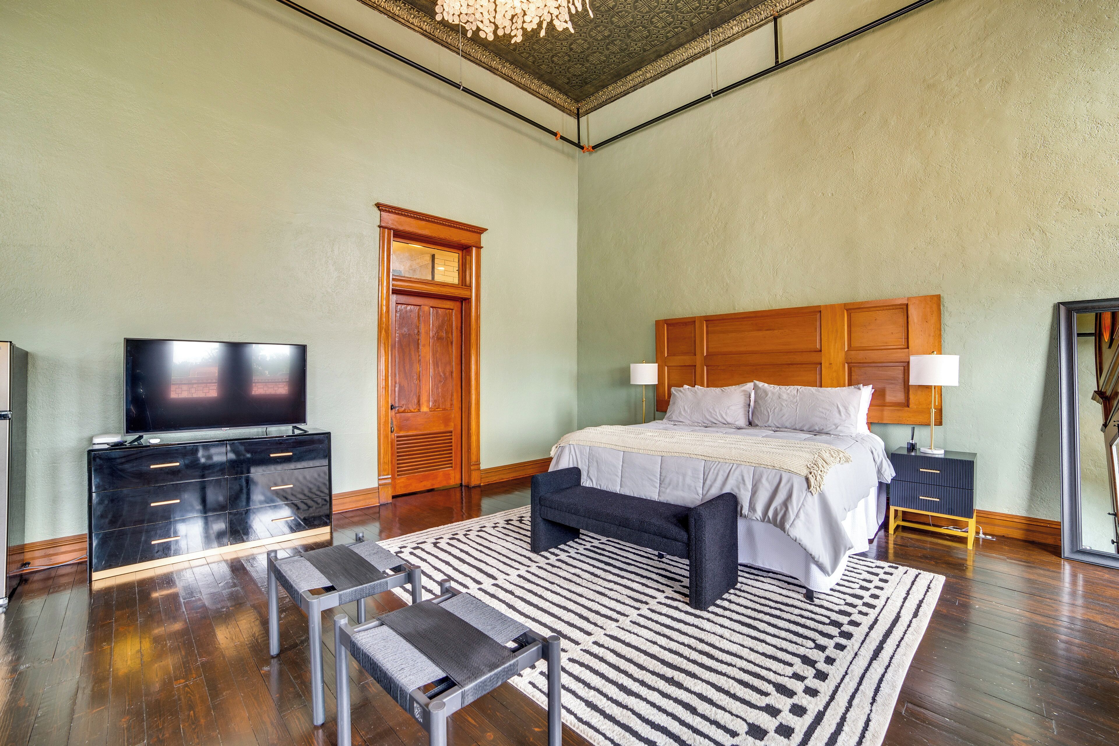 A bedroom with a bed, bedside tables, a television, and a large window.