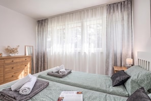 A hotel room with a bed, a nightstand, a dresser, and a window with curtains. - Nurli Apt Near Glavanovo Beach (Rijeka)