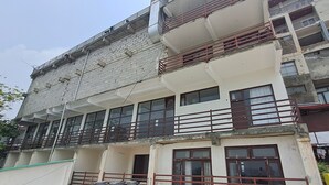 Ένα πολυώροφο κτίριο με μπαλκόνια, μεγάλα παράθυρα και ένα κατάστημα στο ισόγειο.