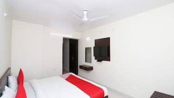 A modern hotel room with a bed, a ceiling fan, a TV, and a small bedside table.