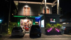 A modern building with a two-story structure, a visible entrance, and a neon sign. - Kmee Transit hotel & Restaurant (Katunayake)