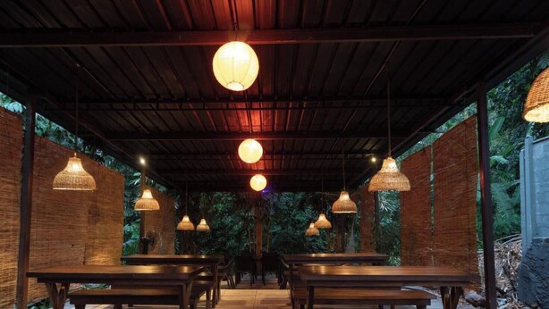 An outdoor dining area with wooden tables and hanging lamps. - Kmee Transit hotel & Restaurant (Katunayake)