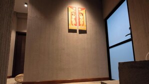 A hotel room with a large window, a wall-mounted artwork, and a wicker chair. - Kmee Transit hotel & Restaurant (Katunayake)