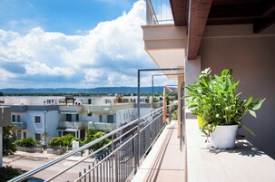Un balcone con una pianta in vaso, una ringhiera e una vista su edifici e montagne all'orizzonte.