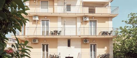 A multi-story building with balconies, air conditioning units, and outdoor furniture.