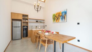 Una cocina moderna con un refrigerador empotrado, dispensador de agua, armarios de madera y una zona de comedor con una mesa y sillas de madera.