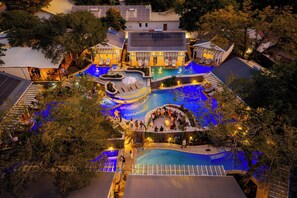 Eine Vogelperspektive eines Resorts mit mehreren Schwimmbecken, Sitzbereichen im Freien und Solaranlagen.