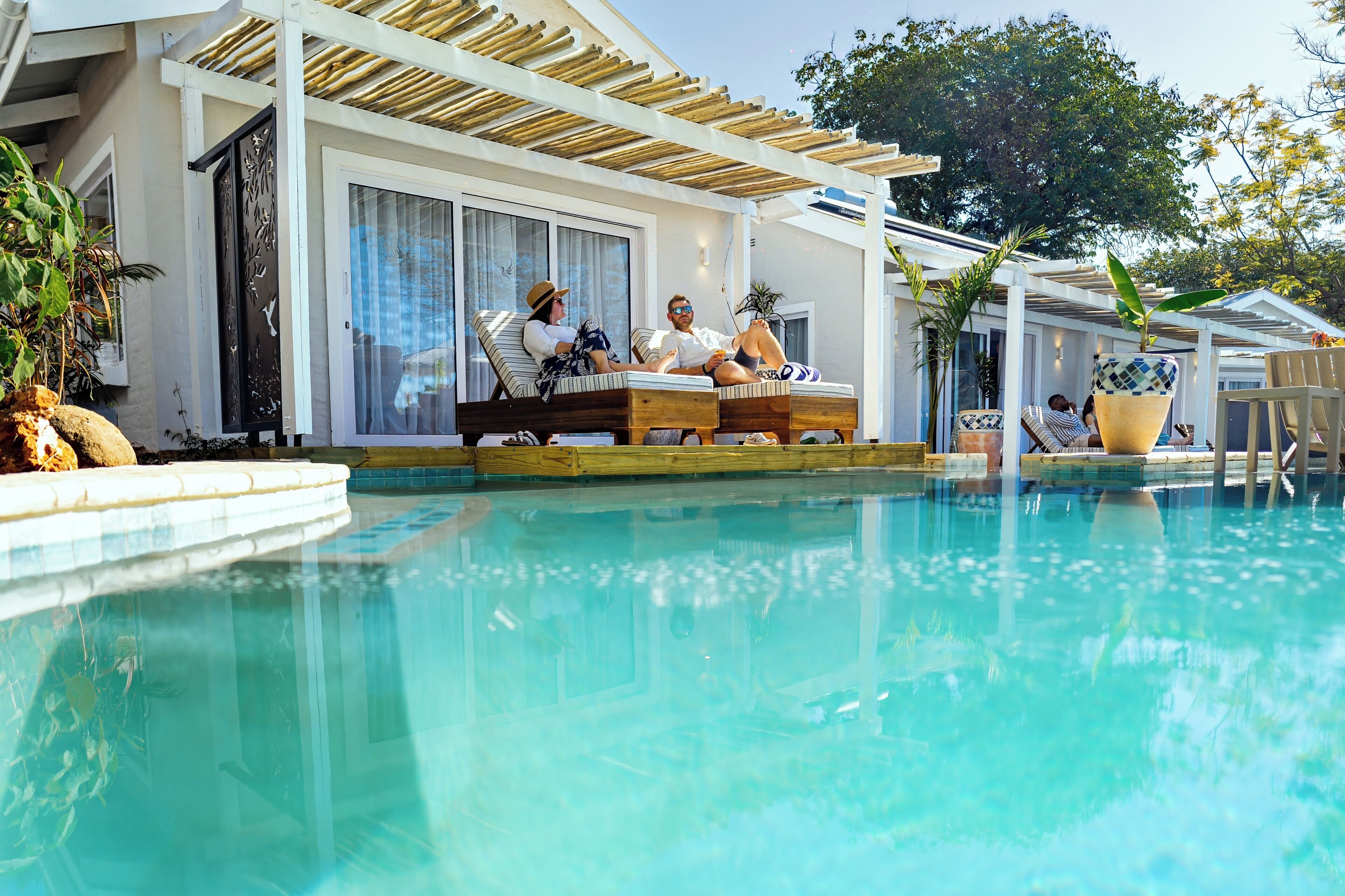 A poolside area with lounge chairs and a covered seating area.