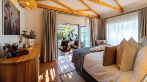 A spacious bedroom with a large bed, wooden ceiling beams, and a view of an outdoor area. - Samanzi (Victoria Falls)