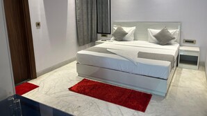 Un dormitorio moderno con una cama grande, un tapete rojo y una mesita de noche blanca.