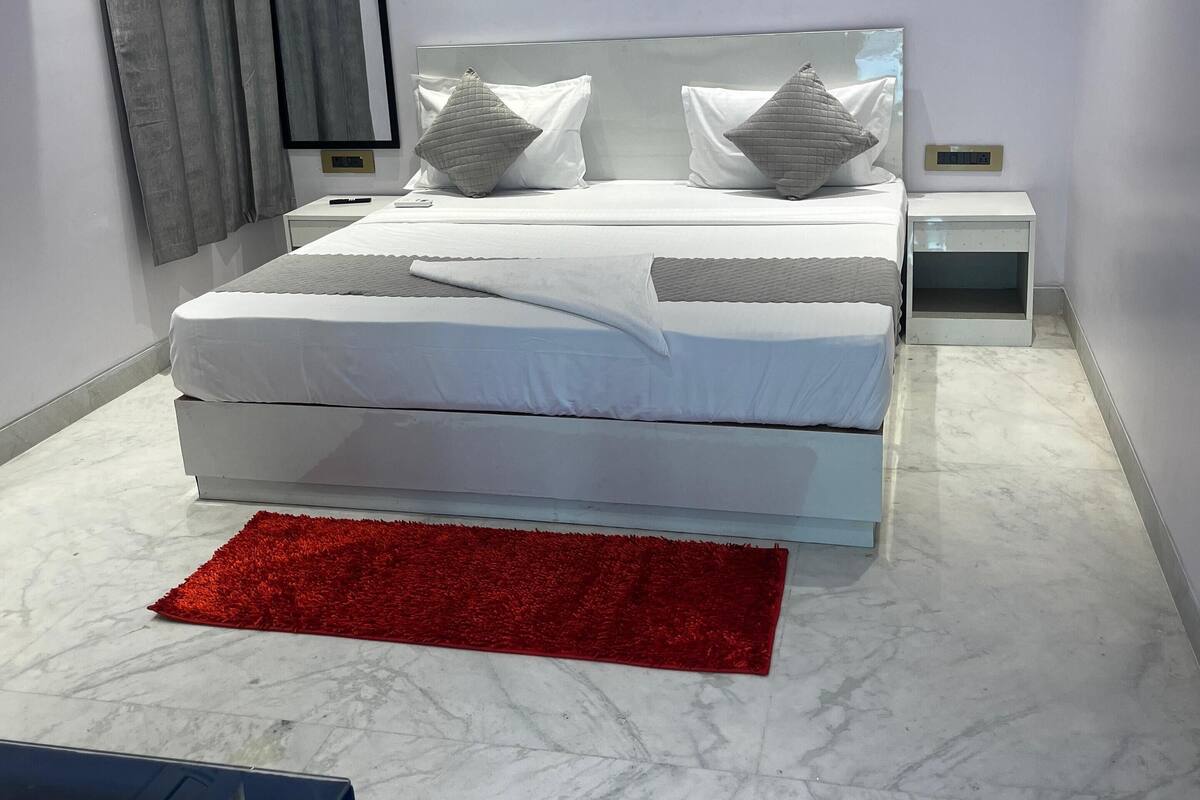 Ein modernes Schlafzimmer mit einem großen Bett, einem Nachttisch, einem roten Teppich und einem Spiegel an der Wand.